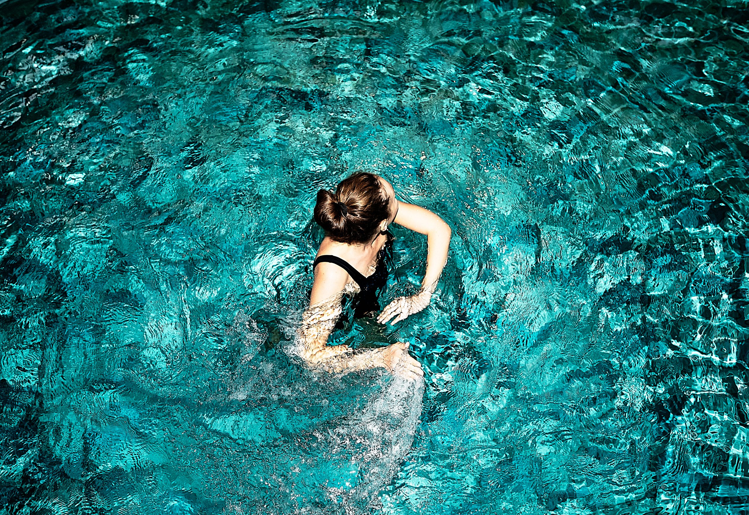 Junge Frau im Pool von oben